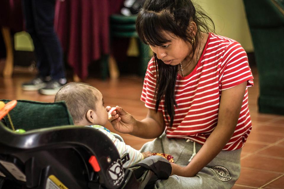 Woman feeding baby in a car seat