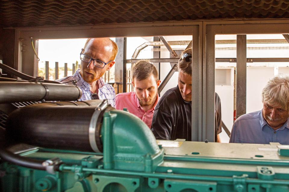 EMI staff looking over a generator